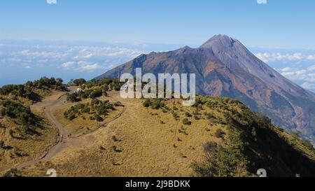 Magnifique paysage naturel depuis le sommet du Mont Merbabu qui regarde la savane, le ciel bleu et la majesté du Mont Merapi Banque D'Images