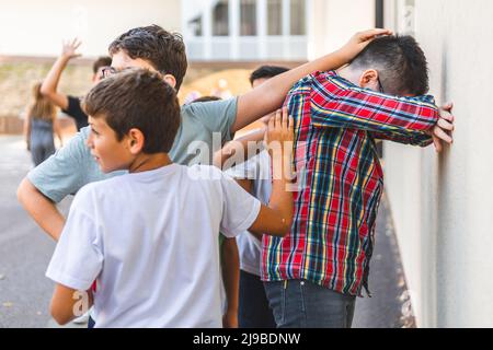 Groupe de garçons qui jouent dans la cour de l'école, se cacher et chercher Banque D'Images