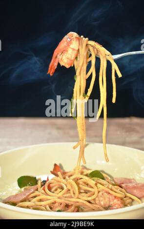 crevettes spaghetti sautées épicées avec tranche de porc au jambon et rouleau de feuilles de basilic dans la fourchette sur l'assiette Banque D'Images