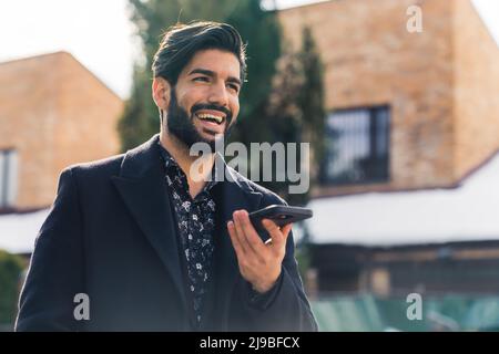 Portrait moyen d'un jeune homme latin qui pense tout en parlant au téléphone à l'extérieur. Photo de haute qualité Banque D'Images