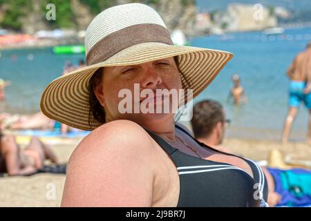 Gros plan été portrait de la tête et de l'épaule d'une jeune femme adulte en relief portant un chapeau de paille sur la plage. Banque D'Images