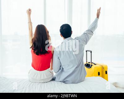 Couple de touristes, de joyeuses vacances. Vacances d'été. Portrait de la vue arrière de jeune asiatique homme et femme levant la main avec heureux sur le lit blanc avec suitc Banque D'Images