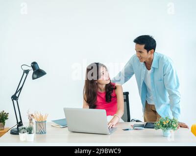 Joyeux couple asiatique, jeune femme et homme utilisant une tablette et un ordinateur portable ensemble pour la réservation de vol, la chambre d'hôtel et les informations de voyage à la maison, prêt t Banque D'Images