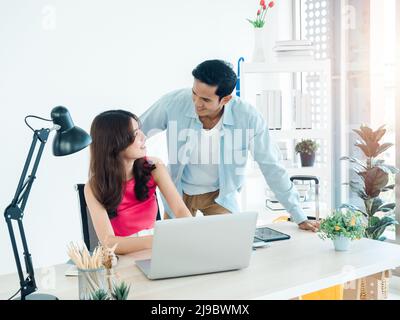 Joyeux couple asiatique, jeune femme et homme utilisant une tablette et un ordinateur portable ensemble pour la réservation de vol, la chambre d'hôtel et les informations de voyage à la maison, prêt t Banque D'Images