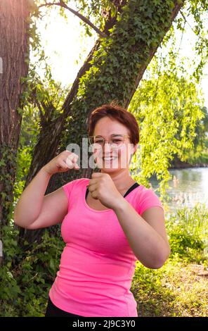 Belle jeune femme essayant de se mettre en forme pour l'été; l'entraînement de boxe dans un parc dans l'ombre Banque D'Images