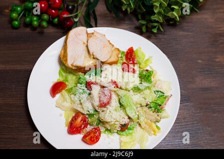 Une assiette de salade César vue d'en haut. Laitue Iceberg, tomates cerises, parmesan, filet de poulet. Banque D'Images