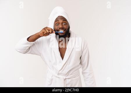 portrait d'un heureux jeune anm foncé se brossant les dents avec du dentifrice noir sur fond blanc. Banque D'Images