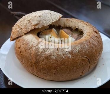 Soupe blanche de borscht polonais avec œuf dans un bol à pain sur une assiette blanche Banque D'Images