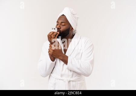 Homme afro-américain souriant appliquant de la crème sur son visage. Concept de soin de la peau de l'homme Banque D'Images