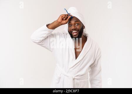 portrait d'un heureux jeune anm foncé se brossant les dents avec du dentifrice noir sur fond blanc. Banque D'Images