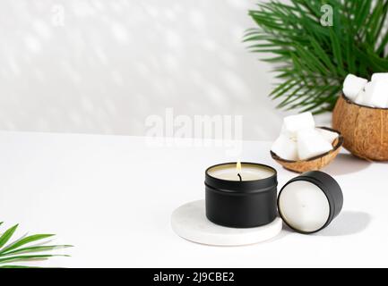 Bougie de cire de noix de coco dans un pot noir sur fond blanc. Bougies de cire de noix de coco écologiques. Concept tendance. Minimaliste. Projection isométrique. Banque D'Images