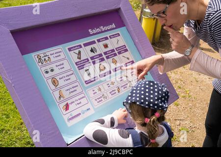 Une mère enseignant des mots gallois à sa fille sur une carte son gallois - anglais au Kidwelly Children's Sensory Garden, Kidwelly Banque D'Images