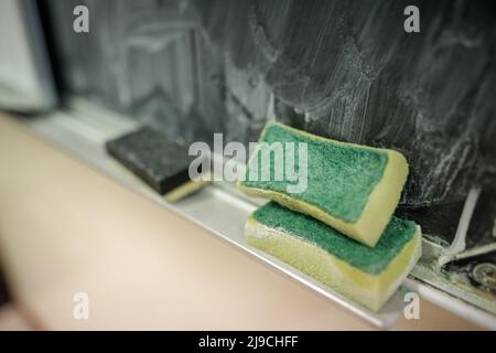 Détails de faible profondeur de champ (foyer sélectif) avec une éponge utilisée pour nettoyer le tableau noir de la craie dans la salle de classe d'une école primaire. Banque D'Images