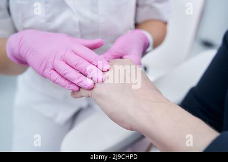 Photo rapprochée des mains du cosmétologue et du client avant le traitement de rajeunissement Banque D'Images