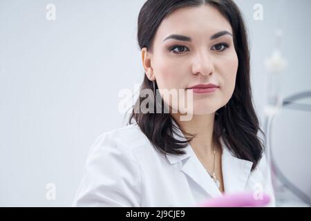 Femme cosmétologue de soin appréciant de travailler dans la clinique de beauté Banque D'Images