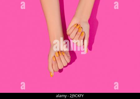 Des mains de femmes soignées avec un motif à ongles tendance sur fond rose Banque D'Images
