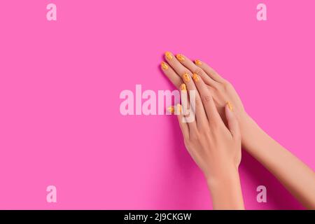 Des mains de femmes soignées avec un motif à ongles tendance sur fond rose Banque D'Images