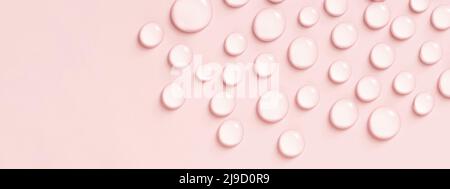 Gouttes d'eau ou de liquide cosmétique sur fond rose. Banque D'Images