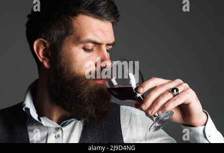 Homme barbu avec un verre de vin rouge. Dégustation d'alcool. Sommelier, degustator. Cave de vinification, viticulteur masculin. Banque D'Images