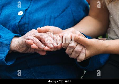 Associations caritatives pour personnes âgées. Les jeunes mains tiennent les vieilles mains de personnes âgées. Soutien au concept des aînés. Banque D'Images