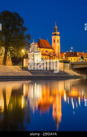 Gyor, ville en Hongrie, église carmélite baroque de nuit se reflétant dans la rivière Raba Banque D'Images