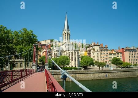 Lyon, France - 11 mai 2022 : personnes traversant un pont rouge et la vieille ville de Lyon en arrière-plan Banque D'Images