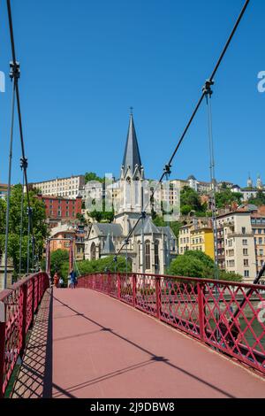 Lyon, France - 11 mai 2022 : personnes traversant un pont rouge et la vieille ville de Lyon en arrière-plan Banque D'Images