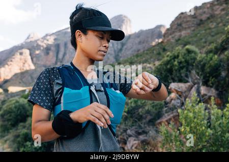 Femme randonneur regardant la montre intelligente. Femme en sport vérifiant une distance sur un tracker d'entraînement. Banque D'Images