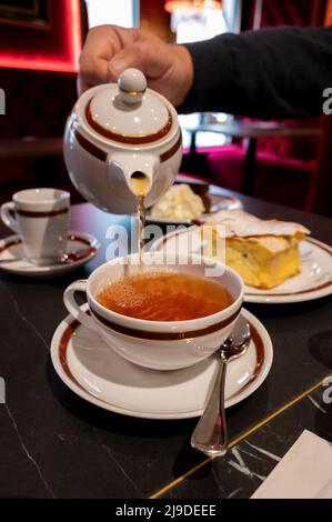 Temps du thé en Angleterre, verser du thé noir earl Grey avec bergamote dans une tasse, thé dînatoire servi café à Londres, gros plan Banque D'Images