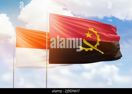 Ciel bleu ensoleillé et drapeaux de l'angola et de l'indonésie Banque D'Images