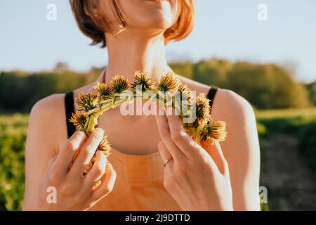 Portrait de la belle femme faisant couronne de fleurs pissenlits sur le champ de floraison. Style de vie d'été, amoureux de la nature et concept de liberté. Fleuriste Banque D'Images