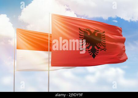 Ciel bleu ensoleillé et drapeaux de l'albanie et de l'indonésie Banque D'Images