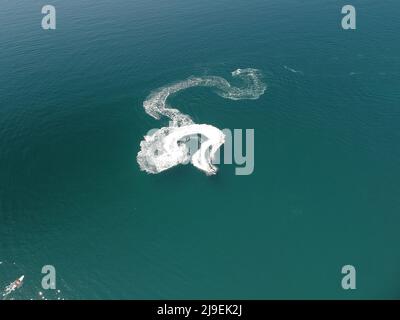 Vue aérienne en haut vers le bas de la trace de mousse d'eau avec une jolie ombre bleu profond de l'océan. Magnifique sentier blanc sur la surface de la mer calme derrière un petit puissant Banque D'Images