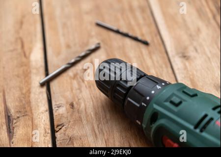 Une perceuse électrique et deux perceuses reposent contre la surface en bois. L'outil électrique portatif fait tourner les cartes. Mise au point sélective. Personne. Banque D'Images