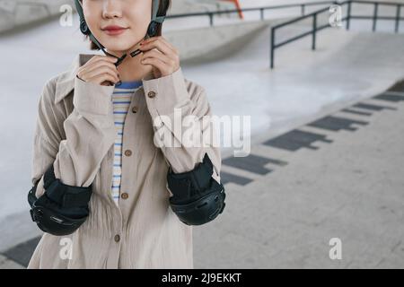 Photo de section médiane d'une jeune fille portant des protections et un casque dans un parc à roulettes, espace de copie Banque D'Images