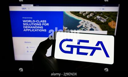 Personne tenant un smartphone avec le logo de la société allemande de transformation des aliments GEA Group AG à l'écran devant le site Web. Mise au point sur l'affichage du téléphone. Banque D'Images