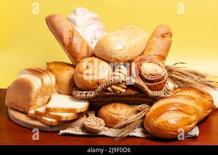 Pain avec petits pains, bagels de séchage, épis de blé sur fond jaune. Expérience culinaire. Banque D'Images