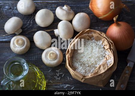 Ingrédients pour un délicieux plat végétalien. Riz basmati blanc, ail et champagnes sur une table en bois, vue de dessus, horizontale Banque D'Images