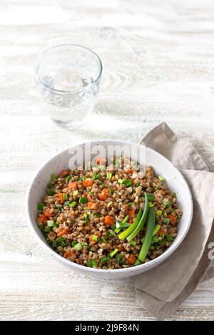 Sarrasin végétarien délicieux avec légumes et oignons verts sur fond de bois clair. Des aliments sains faits maison Banque D'Images