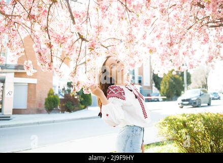 Portrait d'une femme mignonne dans le parc en fleurs de sakura. Concept de ressort. Banque D'Images