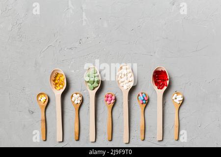 Vue de dessus variété de pilules de vitamines et de minéraux dans une cuillère en bois sur fond coloré. Vue de dessus d'un assortiment de pilules pharmaceutiques. Régime alimentaire Banque D'Images