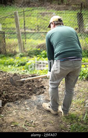 Guy creuse le sol. Plantation de pommes de terre en Russie. Russe avec pelle. L'homme prépare le terrain. Banque D'Images