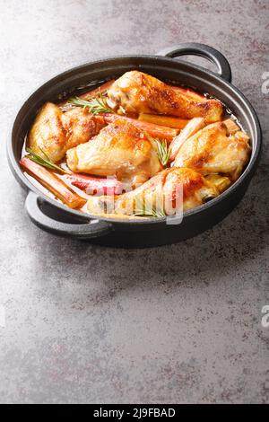 Le poulet à la rhubarbe, les oignons et l'ail sont mijotés avec du vin blanc et du beurre dans une sauce riche en gros plan dans une poêle à frire sur la table. Verticale Banque D'Images