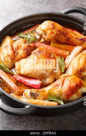 Poulet cuit avec rhubarbe et vin blanc en gros plan dans une poêle sur la table. Vertical Banque D'Images