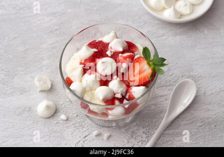 Eton Mess, dessert anglais traditionnel, fraise à la crème, meringue et sauce fraise sur fond texturé gris clair, vue du dessus, horizontale Banque D'Images
