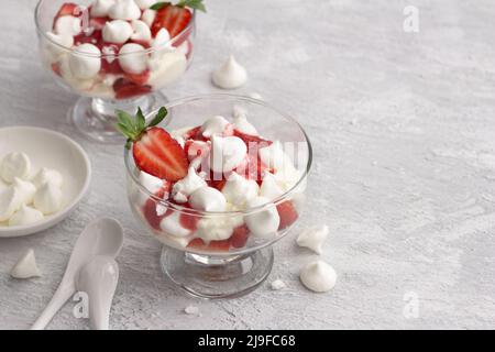 Eton Mess, dessert anglais traditionnel, fraise à la crème, meringue et sauce fraise sur fond texturé gris clair, vue du dessus, espace, horizontal Banque D'Images