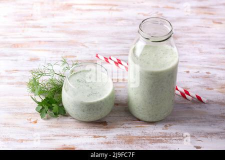 Kéfir vert diététique sain (yaourt) avec des herbes dans le verre et une bouteille sur une table en bois Banque D'Images