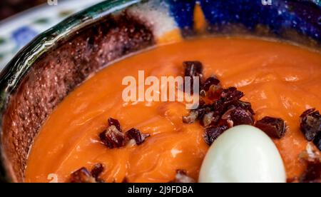 Gros plan d'un bol en céramique avec des salmorejo cordobes espagnoles fraîchement faites. Soupe froide de tomates, nappée de jambon serrano et d'œufs durs. Mise au point sélective Banque D'Images