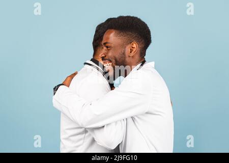 portrait de przloseup d'un professionnel de la santé intellectuel avec un laque blanc discutant des résultats avec un jeune médecin sur fond bleu Banque D'Images