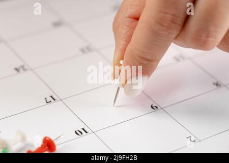 Les mains corrigeant l'horaire des notes, vignette blanche dans le calendrier pour les réunions et les rappels de rendez-vous Banque D'Images